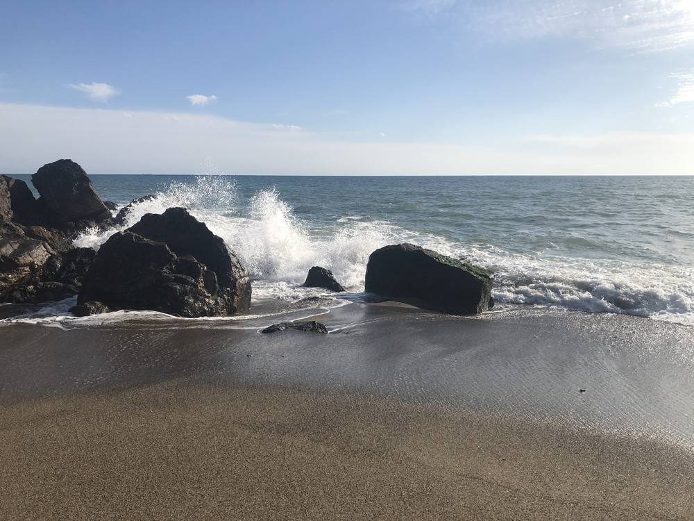 Waves breaking against dark rocks on the shore