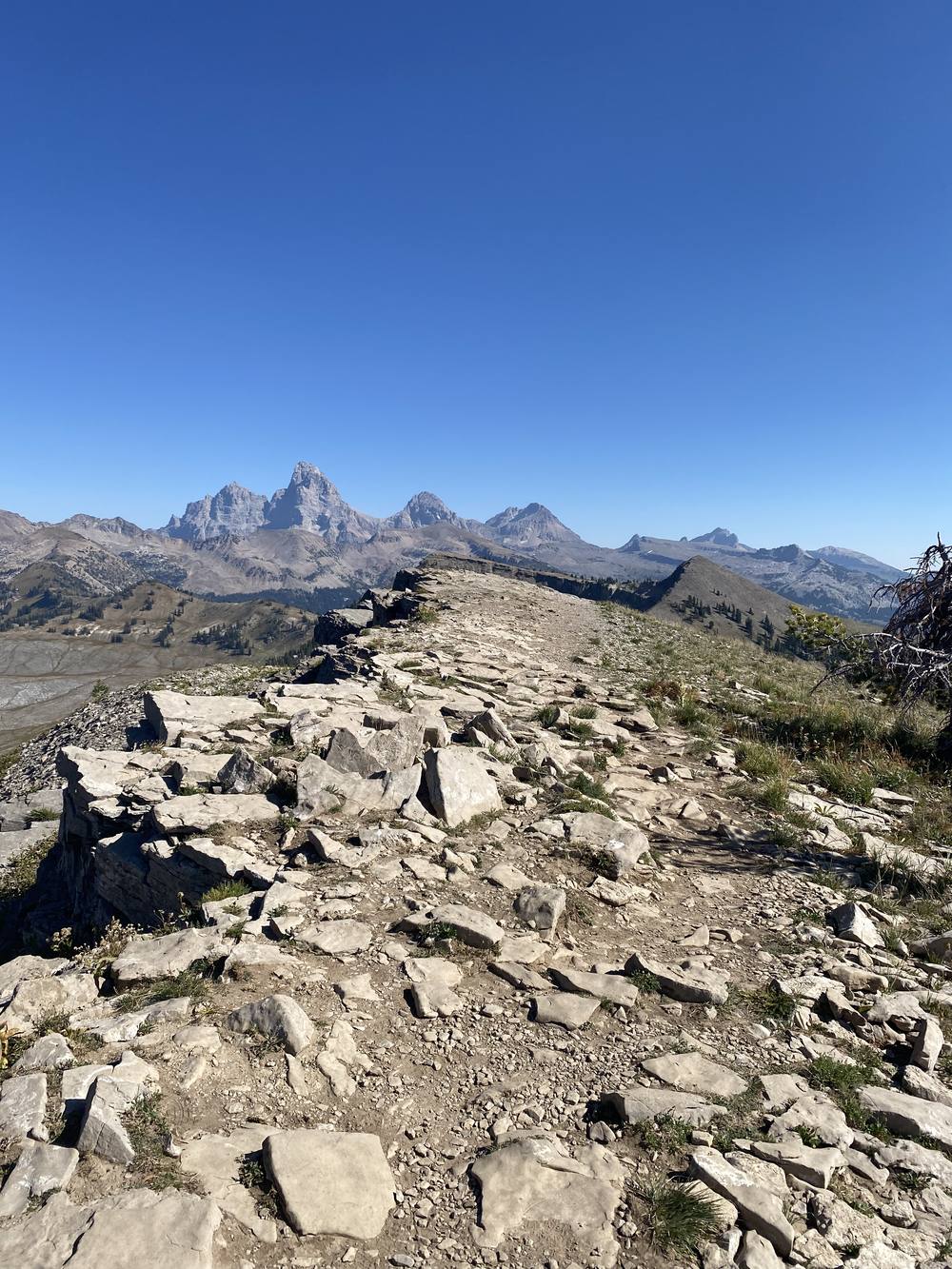 A rocky ridge trail leading toward the Tetons