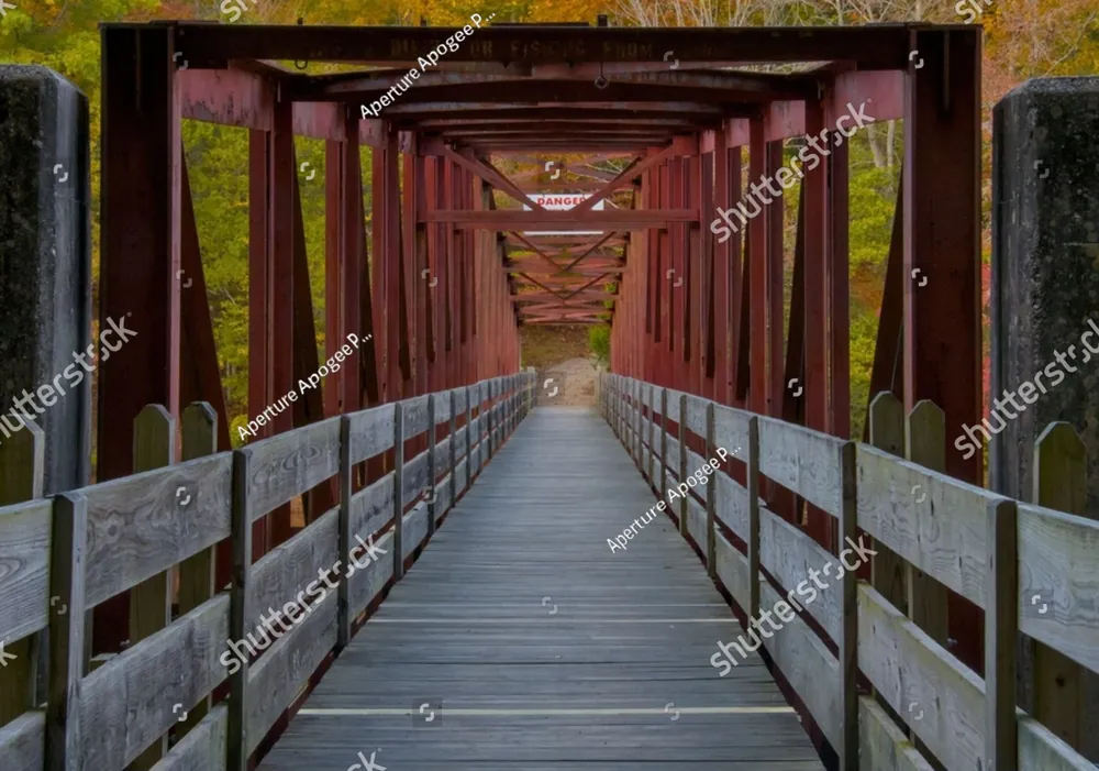 A long wooden footbridge under a red steel frame