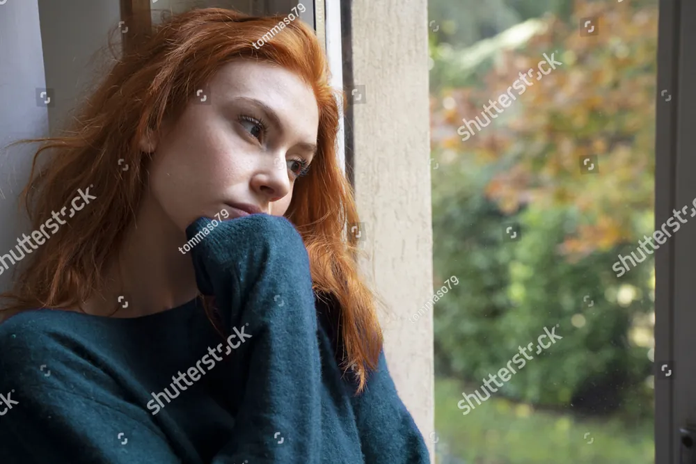 A woman sitting by a window, deep in thought