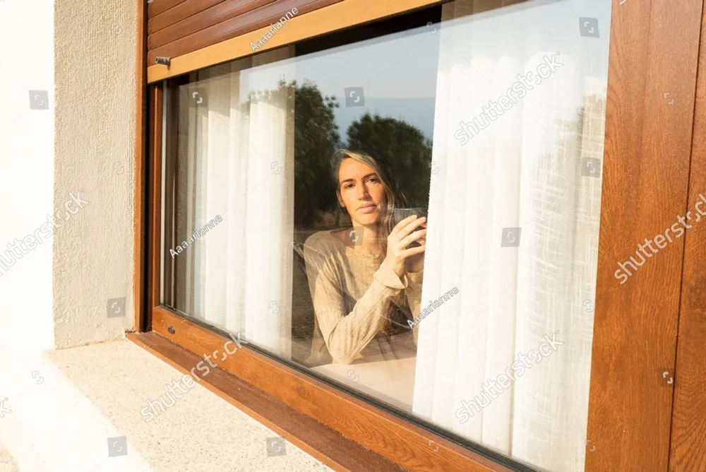 A woman looking out through a window at home