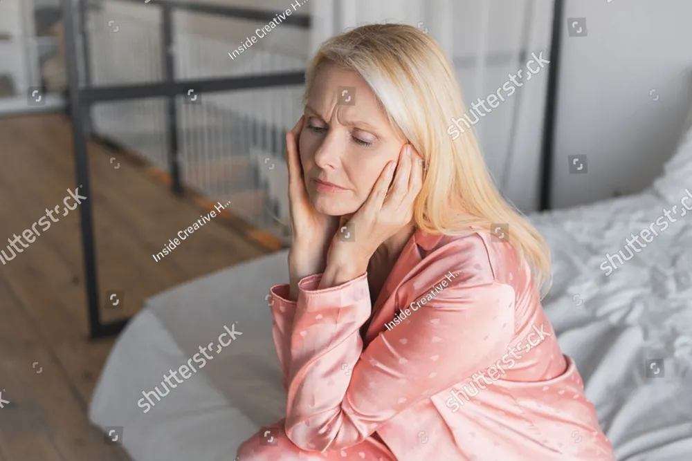 A woman sitting on her bed with her head in her hands